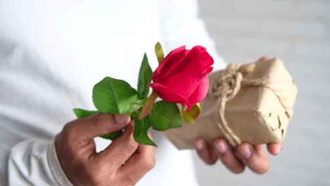 man holding a red rose and gift box