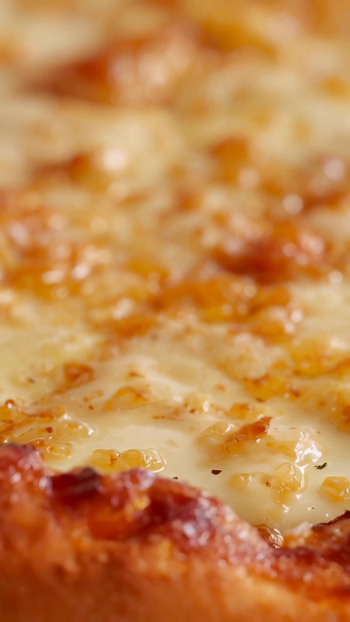 Video verticale: Telecamera che si allontana rivelando una pizza sul set, mostrando formaggio fuso, olio e briciole di crosta per riprese macro.