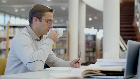 man drinking tea while studying in library