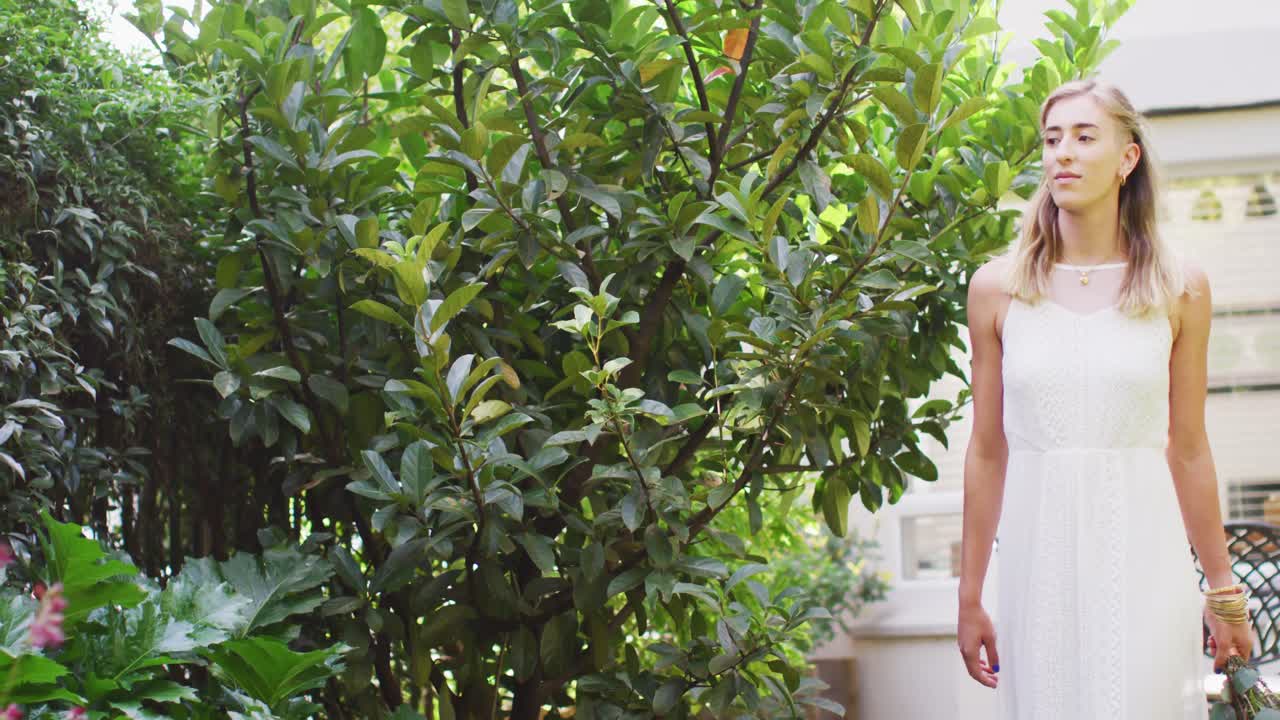 행복한 백인 여성이 산책하고  ⁇ 은 날 정원에서 꽃을  ⁇ 고 있습니다.