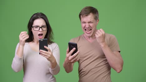 young couple using phone and getting good news together