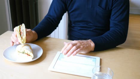 man using digital tablet while having breakfast in living room 4k