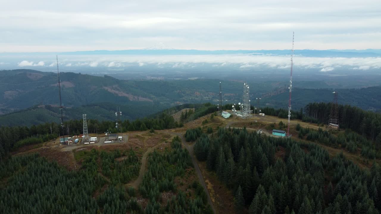 US, WA, Olympia, 2025-10-31 - Drone view of the radio towers at Capitol Peak outside the city. With Mt Ranier in the far distance