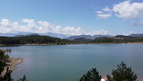 aerial view of lake with pine forest and mountain range at the backgroud, albania