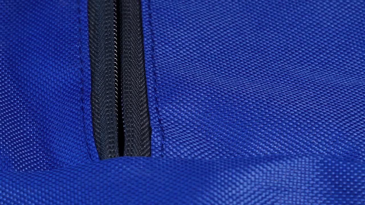 Young male hand opening the grey zipper of a blue bag