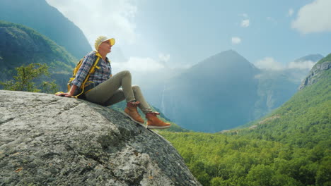 The-Tourist-Sits-On-A-Large-Rock-Surrounded-By-High-Mountains-Alone-Amidst-The-Incredibly-Beautiful