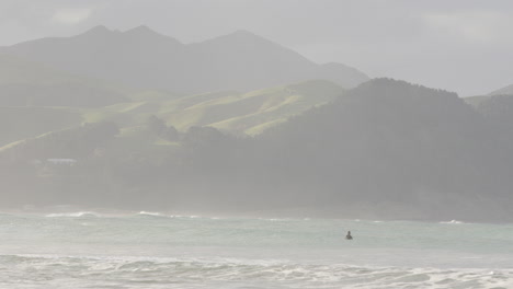 Surfer-is-waiting-for-waves-out-in-the-ocean-in-Castle-Point-Beach,-New-Zealand