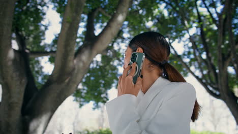 chica glamurosa hablando por teléfono móvil esperando reunión en el parque de cerca. mujer llamando