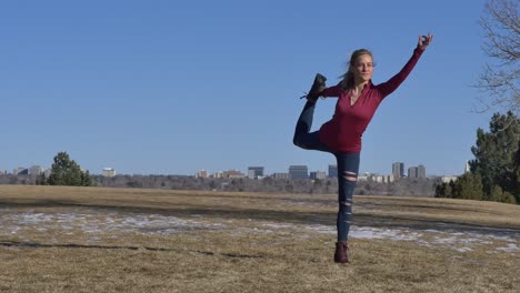 mujer rubia haciendo pose de bailarina sobre hierba amarilla en el parque en invierno