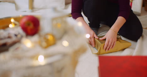 Woman-Wrapping-Christmas-Present-By-Fireplace-At-Home-8