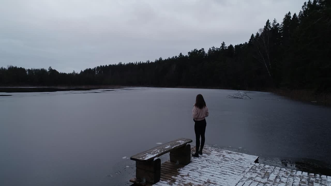 a young girl crosses a wooden bridge in winter time