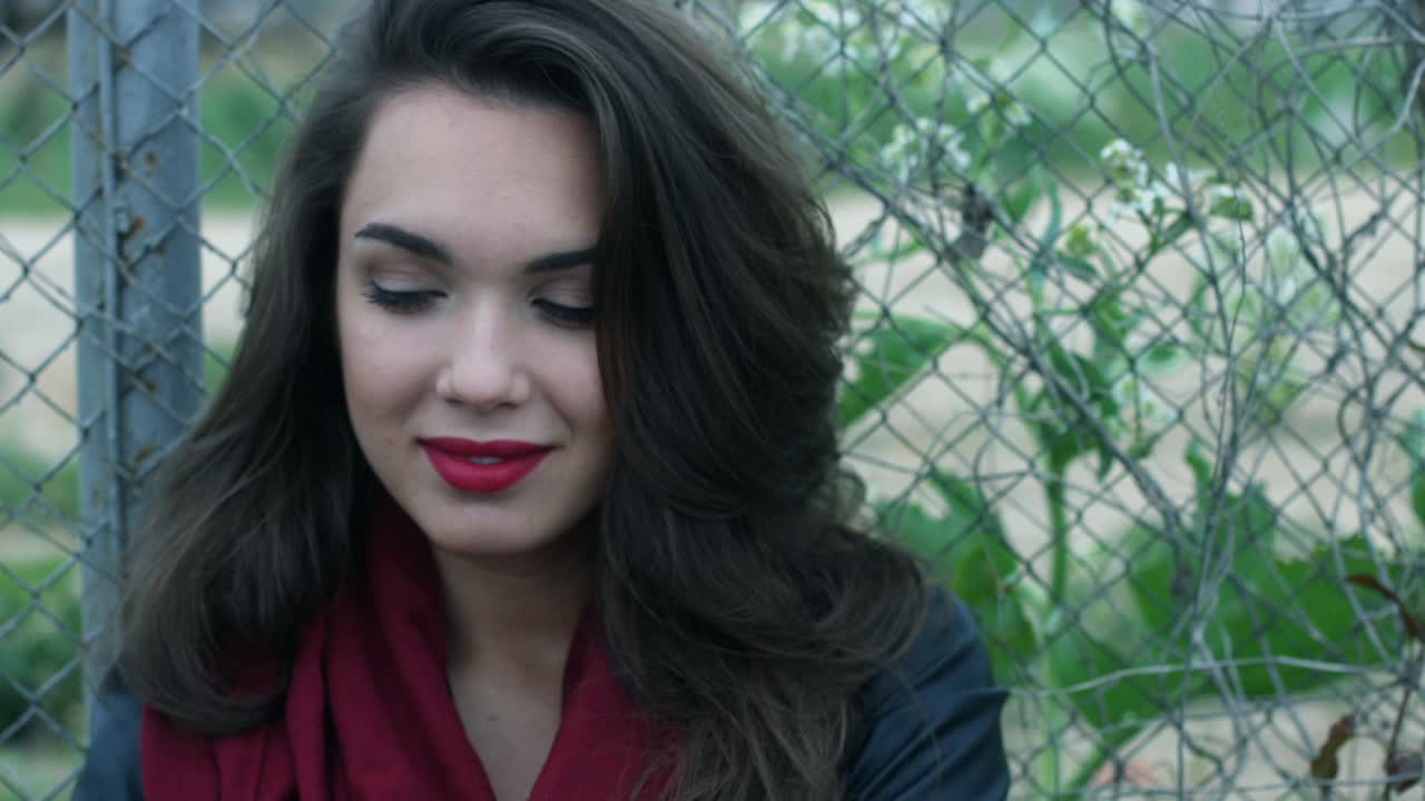 retrato de una mujer atractiva tocando el pelo largo moreno en un fondo de malla de cerca.