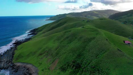 aerial view of steep green hills rolling into blue waves of indian ocean