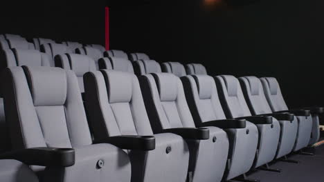 dramatic lit modern cinema seating with armrest in dark movie theatre, 4k