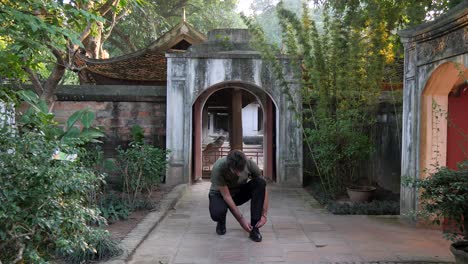 young man stops to stoop down tying shoe laces before walking away