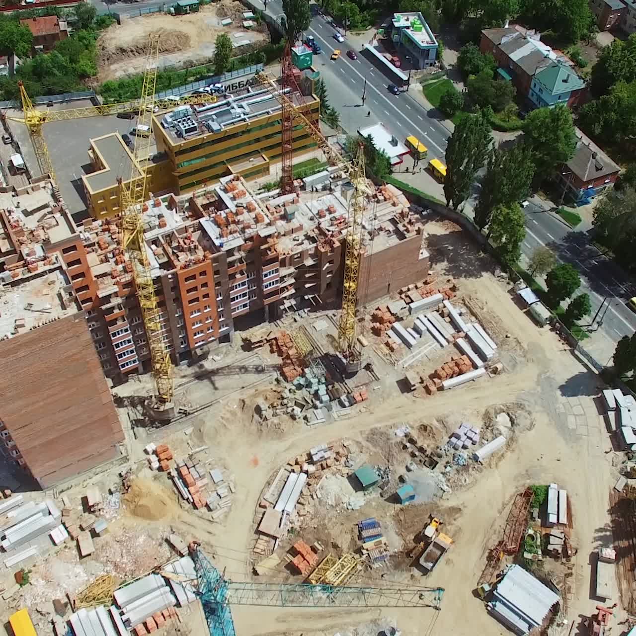 Building of new architecture near the road in the city. View from above on a construction site of a modern district in the downtown. Aerial view.