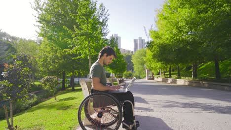 disabled teenager sitting in wheelchair working with laptop.