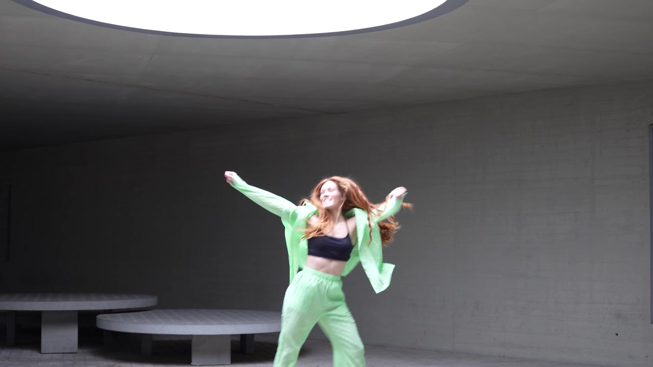 モダンな空間で、スカイライトの下、優雅さとエネルギーを放ちながら踊る女性。