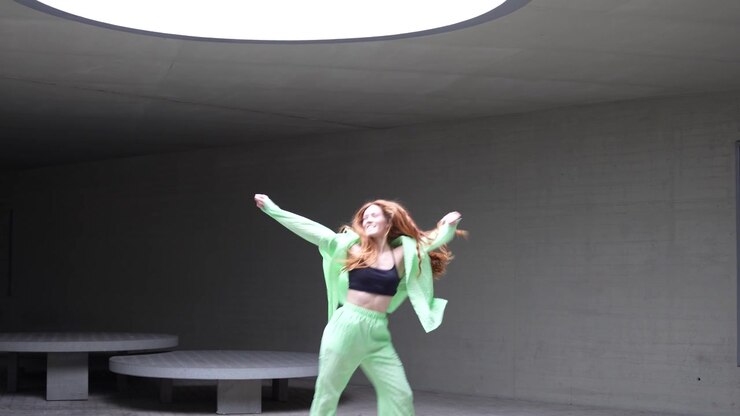 In a modern space a woman dances gracefully under a skylight exuding elegance and energy