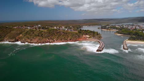 vista aérea sobre las olas rompiendo la costa de la ciudad principal de evans, día soleado - seguimiento, pan, tiro de drones