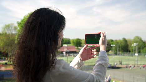 pretty italian woman tourist taking photograph of a park in wimbledon london