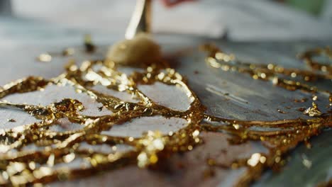 applying gold leaf to an abstract painting