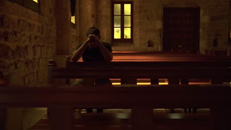 anonymous young man praying alone in church