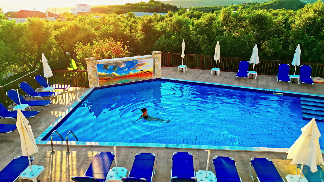 Attraktiv kvinde i en swimmingpool ved solnedgang i Grækenland.