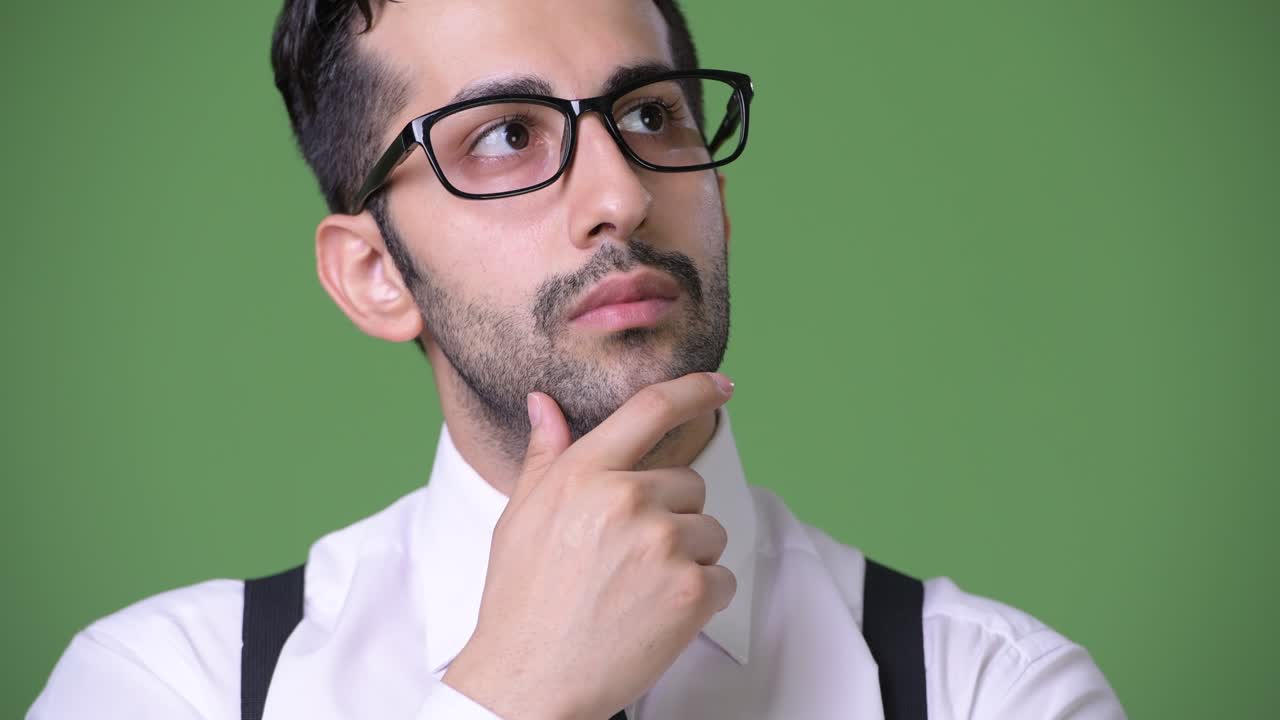 joven empresario persa barbudo y guapo contra un fondo verde