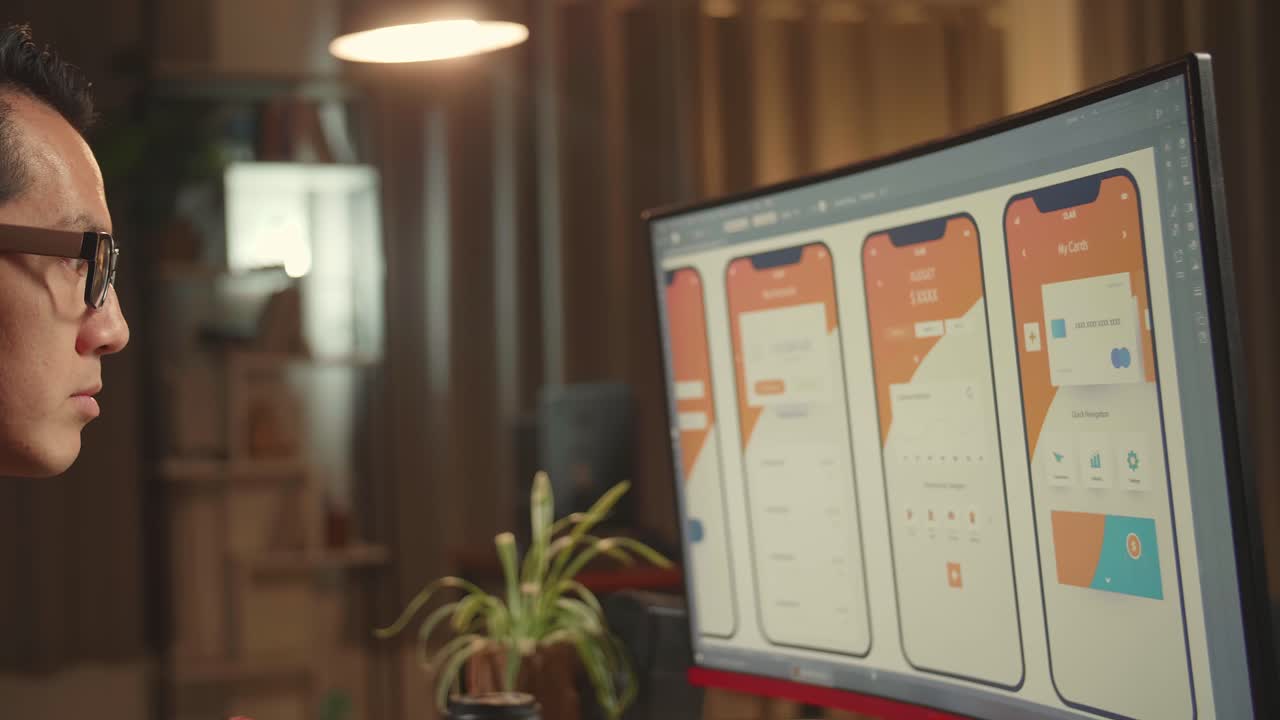 Asian Male Mobile Application Developer Works With Graphics On His Personal Computer. He Works At Night