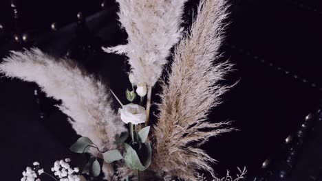 elegant pampas grass with white roses and baby's breath in a dark, moody setting