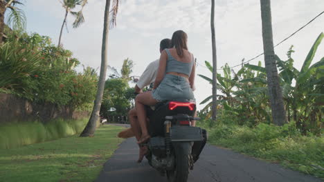 couple riding scooter on tropical island