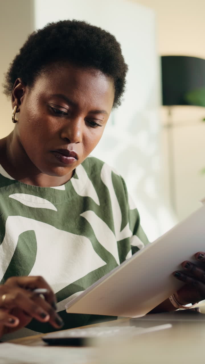 Focused Black Woman Working on Documents and Calculator at Home Office