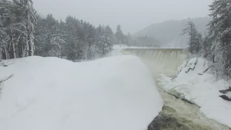 dreamy aerial flight over cascading river of water flowing thru dense snow