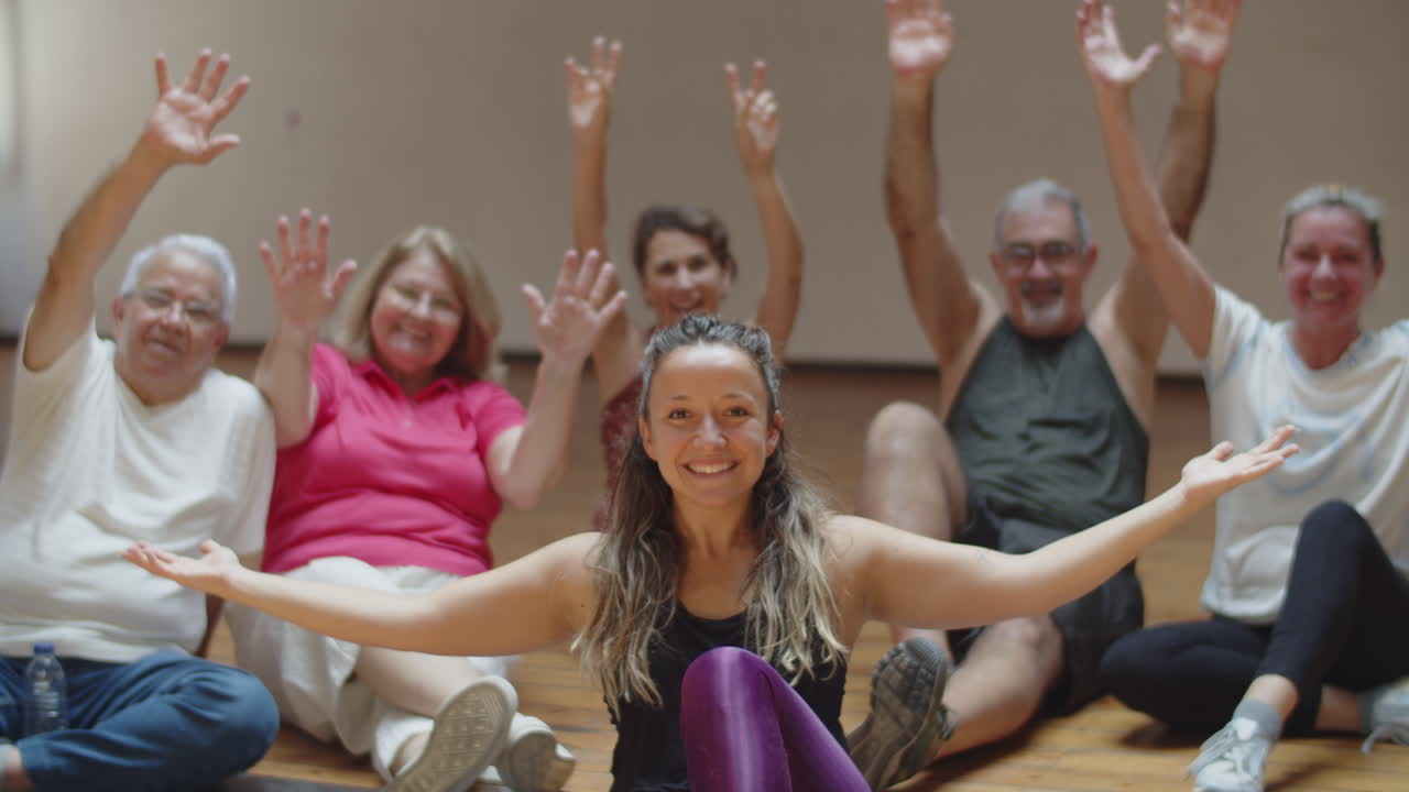 profesora sentada en el suelo con un grupo de baile de jubilados