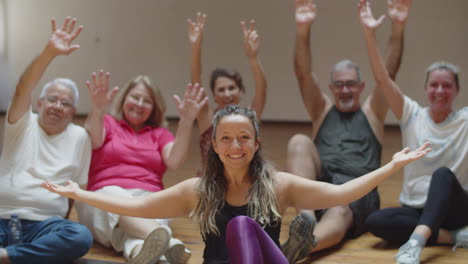 female teacher sitting on floor with dance group of retirees