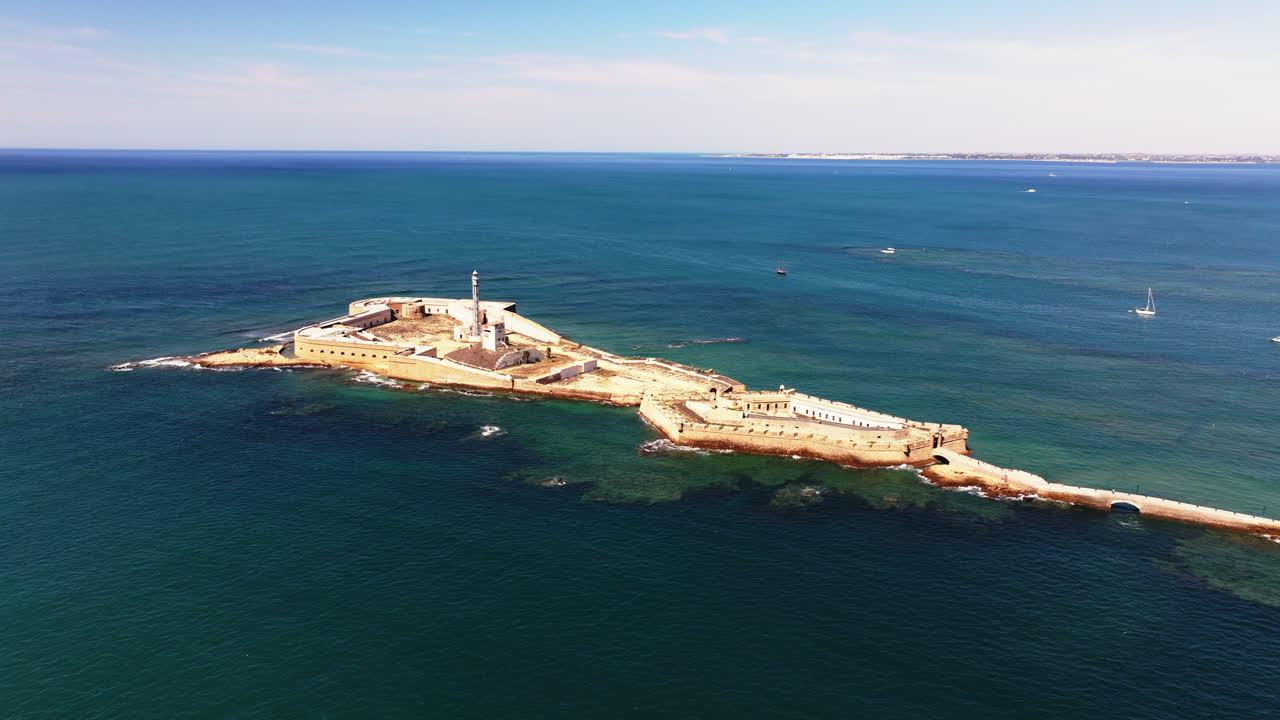 İspanya, Endülüs, Avrupa, Cádiz'deki San Sebastian kale surları ve deniz fenerinin parlak güneşli bir günde profesyonel hava drone'u ile geniş açılı çekimi. Sinematik koyu renk tonlaması