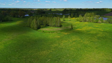 Aerial-view-of-green-spring-fields-on-a-cloudy-day-overlaid-by-shadows-in-Latvia