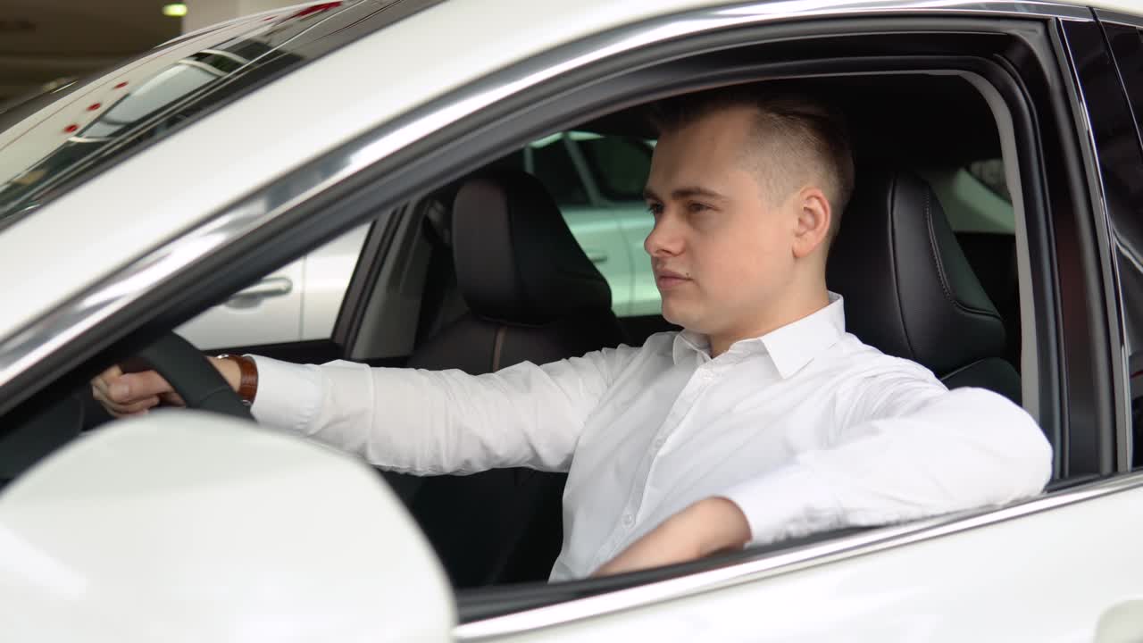 Portrait of a young confident man sitting in a new car at a car dealership