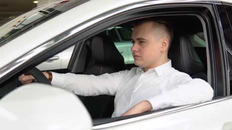 portrait of a young confident man sitting in a new car at a car dealership
