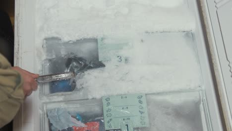 Closeup-of-hands-carefully-chipping-ice-from-freezer