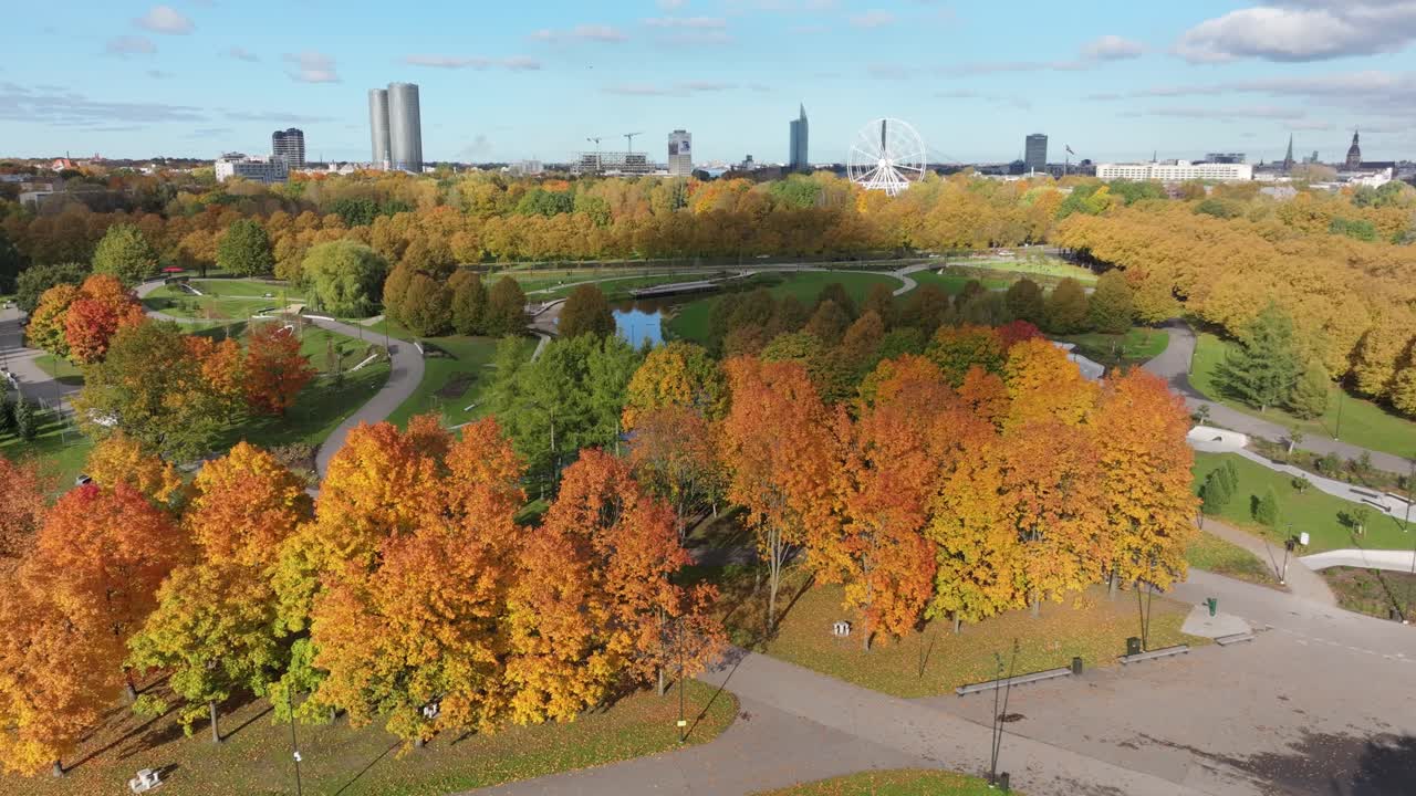 Aerial orbit of autumn foliage in Riga park with famous skyline structures