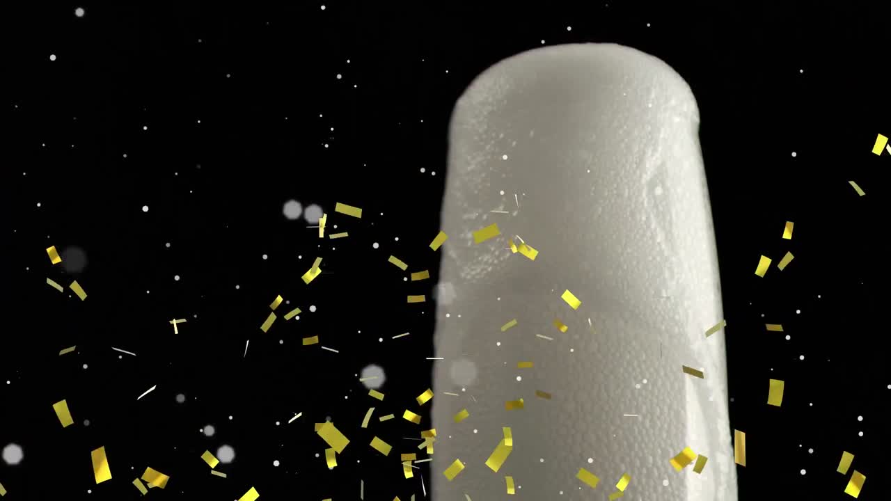 ⁇ 색 반점이 떠다니고 황금색 콘페티가  ⁇ 페인 거품 위에 검은색 바탕에 있는 유리잔에 있습니다.