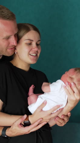 caucasian parents waving their newborn indoors. man and woman in black t-shirts smiling to their baby.. vertical video