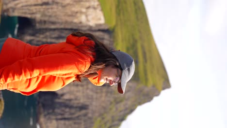 Woman-marvels-at-the-vast-Faroese-landscape-and-rugged-cliffs-during-her-hike-around-Lake-Sorvagsvatn-in-Vagar,-Faroe-Islands