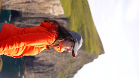 mujer se maravilla del vasto paisaje feroés y los escarpados acantilados durante su caminata alrededor del lago sorvagsvatn en vagar, islas feroe