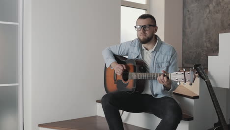 male musician playing guitar at home