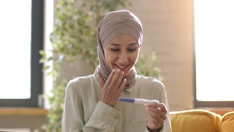 happy muslim woman receiving positive pregnancy test result
