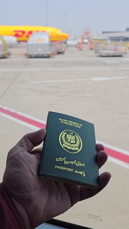 pakistani passport at the airport with a dhl plane in the background