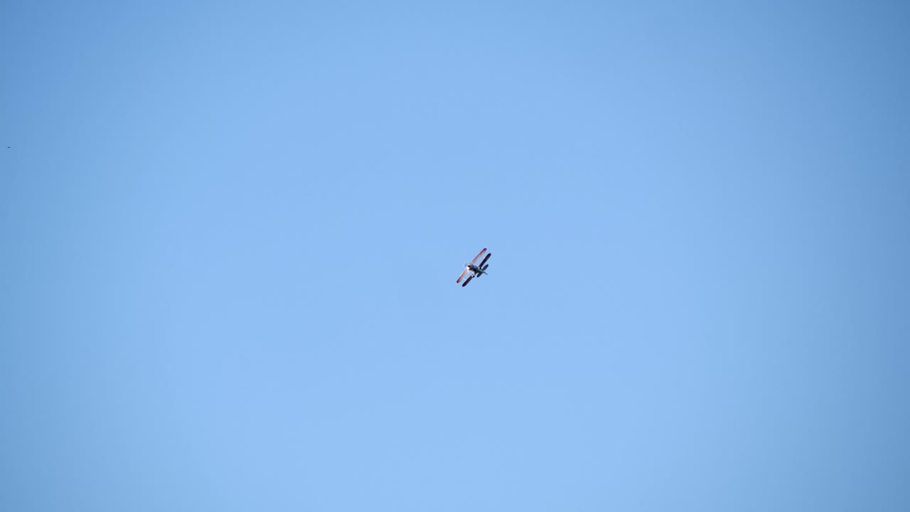 Low Angle View of an Aerobatics Biplane in Flight, Blue Sky Backdrop